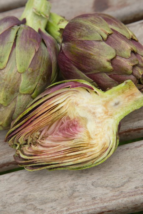 Use a large serrated knife to chop off the top of the artichoke, revealing the interior cross-section. You can see how many layers of leaves there are, along with the top of the choke which covers the heart.